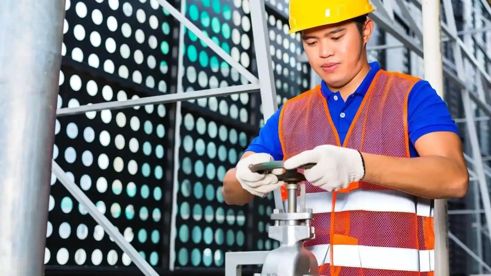 tecnico industrial SIMA Técnico industrial de SIMA operando válvula en planta, con casco, guantes y chaleco de seguridad, durante inspección de recipientes sujetos a presión – Ingeniería SIMA